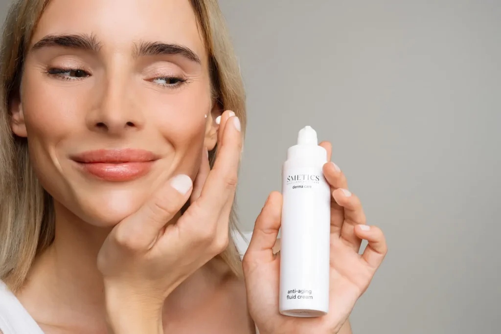 Eine Frau cremt sich im Gesicht ein und hat die Anti Aging Fluid Cream von S'METICS in der Hand